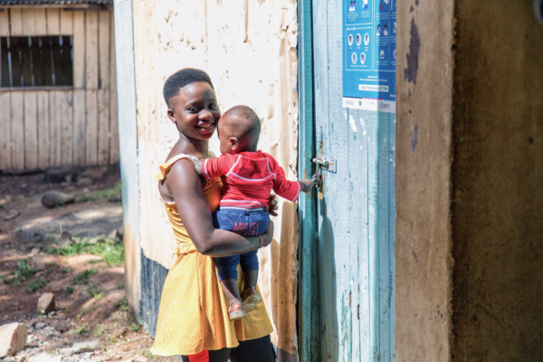 Female holding a baby outdoors near a building.