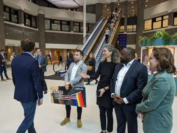 A group of people standing in a lobby, holding a sign.