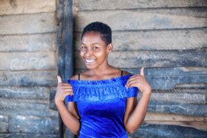 young woman in blue shirt holding her thumbs up