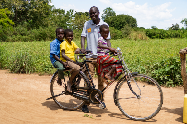 community health worker with 3 children on his bike