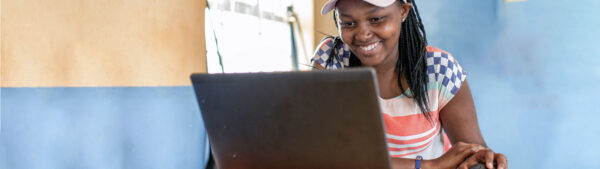 A person smiling while using a laptop computer, enjoying her online experience