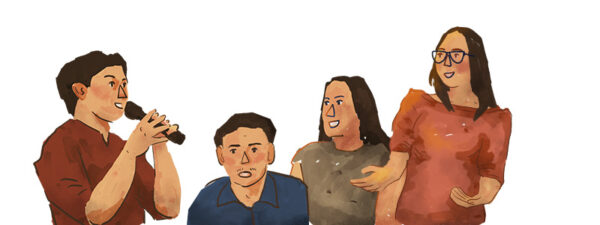 Four people are standing together; one is speaking into a microphone while the others listen and engage in conversation.