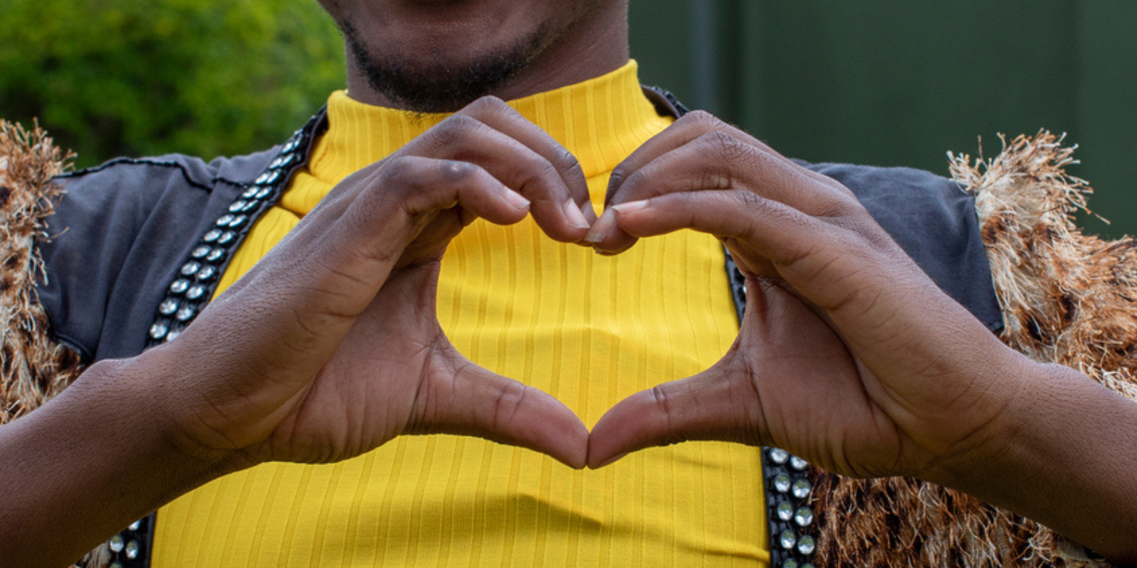 Hands forming a heart shape over a yellow shirt, from the ActHIVate Fund announcement by Aidsfonds